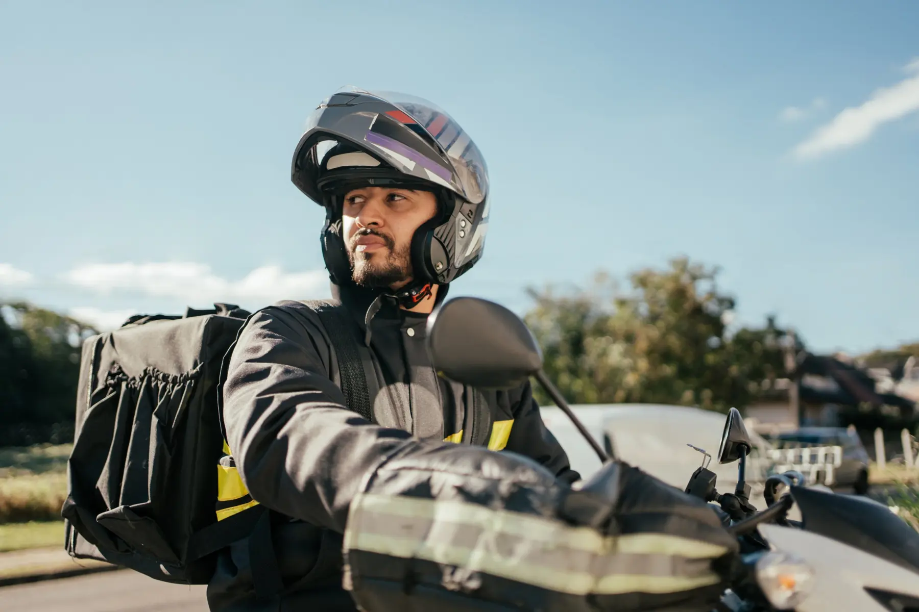 Entregador na moto olhando para o lado, pronto para sair