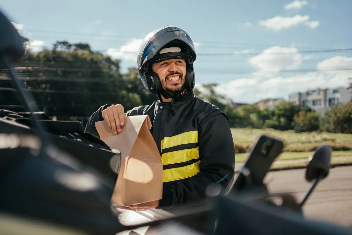 Entregador tirando o pedido da bag e sorrindo